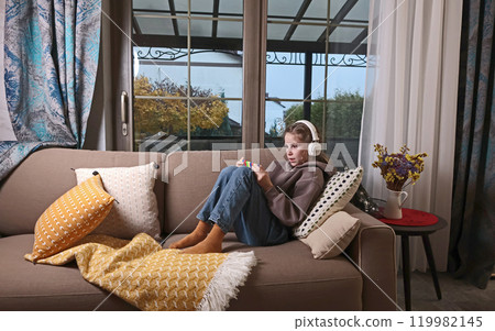 Joyful teenage girl wearing headphones with smartphone online. Pastime and Lifestyle. Joyful teenage girl wearing headphones with smartphone online. Pastime and Lifestyle. 119982145