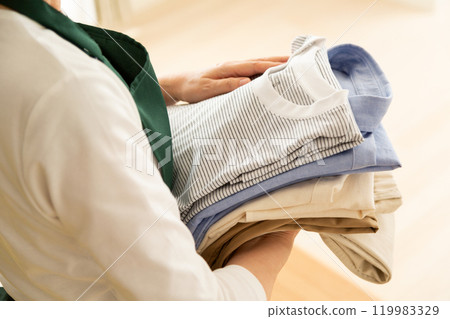 穿著圍裙的中高級女性在客廳的沙發上疊衣服 119983329