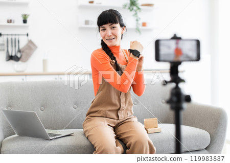 Caucasian female blogger unboxing smartwatch during live stream at home 119983887