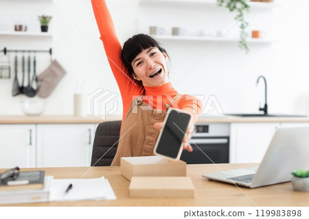 Excited blogger unboxing new smartphone in modern kitchen 119983898