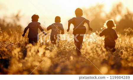 Children running joyfully through a sunlit meadow during golden hour, enjoying a carefree moment in nature 119984289
