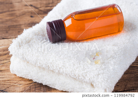 Spa and Wellness concept on wooden background. Terry towel and cosmetic oil for massage. Spa and Wellness concept on wooden background. Terry towel and cosmetic oil for massage. 119984792
