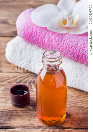 Spa and Wellness concept on wooden background. Terry towel and cosmetic oil for massage. Spa and Wellness concept on wooden background. Terry towel and cosmetic oil for massage. 119984793