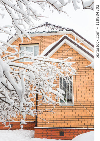 Brick house with window. Tree branches with snow. Brick house with window. Tree branches with snow. 119984802