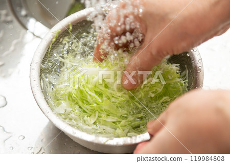中高級婦女在家裡的廚房裡洗切碎的捲心菜 中高級婦女在家裡的廚房裡洗切碎的捲心菜 119984808