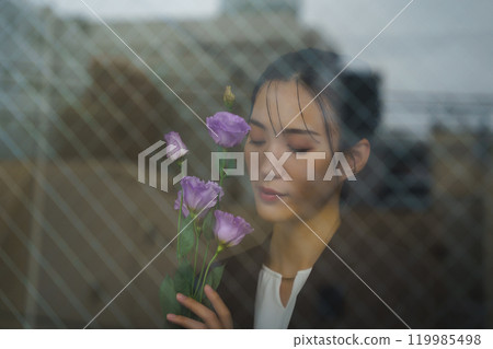 一位穿著西裝的年輕女子,表情憂鬱,透過玻璃倒映著城市景觀 一位穿著西裝的年輕女子,表情憂鬱,透過玻璃倒映著城市景觀 119985498