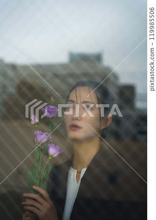 一位穿著西裝的年輕女子,表情憂鬱,透過玻璃倒映著城市景觀 一位穿著西裝的年輕女子,表情憂鬱,透過玻璃倒映著城市景觀 119985506