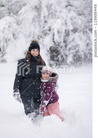 Heartwarming moment of a mother and daughter playing in the snow, capturing love and winter family bonding Heartwarming moment of a mother and daughter playing in the snow, capturing love and winter family bonding 119986449