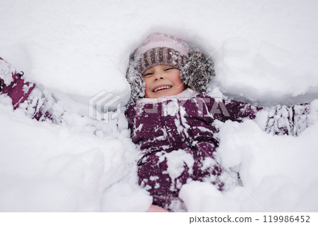 Little girl covered in snow, laughing and playing. A perfect scene of childhood excitement in a winter wonderland Little girl covered in snow, laughing and playing. A perfect scene of childhood excitement in a winter wonderland 119986452
