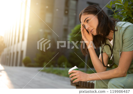 Dark-haired young female doctor feeling tired after the night shift Dark-haired young female doctor feeling tired after the night shift 119986487