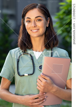 Dark-haired good-looking young female doctor looking contented Dark-haired good-looking young female doctor looking contented 119986521