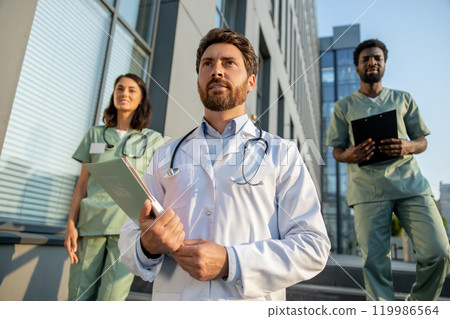 Doctors in lab coats near the hospital looking determined and looking confident 119986564