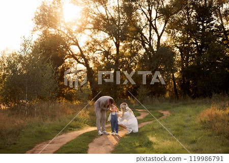 Happy young family walking down the road outside in green nature. 119986791