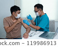 Doctor Giving COVID-19 Vaccine Injection to Patient in Medical Office 119986913