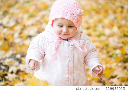 baby girl playing in the park with autumn leaves baby girl playing in the park with autumn leaves 119986915