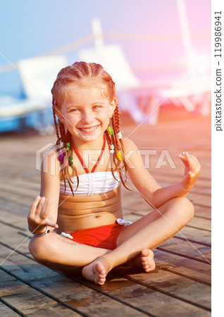 smiling cute girl on a timber floor in yoga pose smiling cute girl on a timber floor in yoga pose 119986941