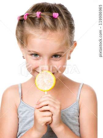 Adorable little girl with yellow lemon lollipop isolated over white background Adorable little girl with yellow lemon lollipop isolated over white background 119986965