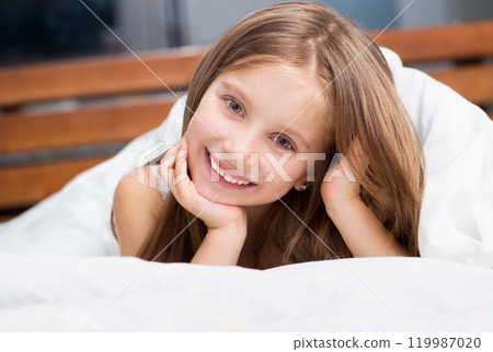 Laughing little girl under a blanket. Isolated on white 119987020