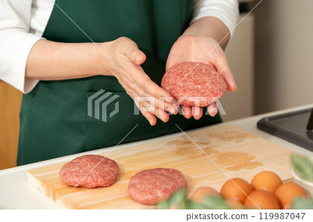 Hands of a middle-aged to senior woman preparing a hamburger steak 119987047