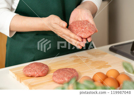 Hands of a middle-aged to senior woman preparing a hamburger steak 119987048
