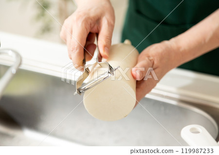 The hands of a middle-aged to senior woman peeling a radish with a peeler The hands of a middle-aged to senior woman peeling a radish with a peeler 119987233