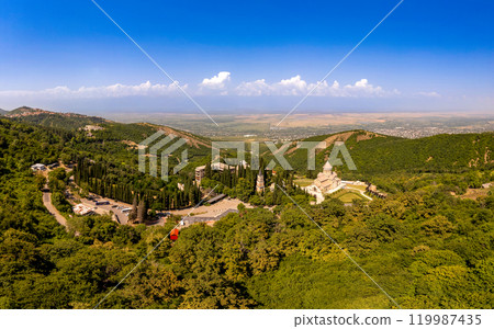 Aerial top view of the Bodbe Monastery architectural complex of St. Nino. View from above to church, Alazani Valley, Greater Caucasus mountains, in sunny summer day. Sighnaghi city, Kakheti, Georgia. 119987435
