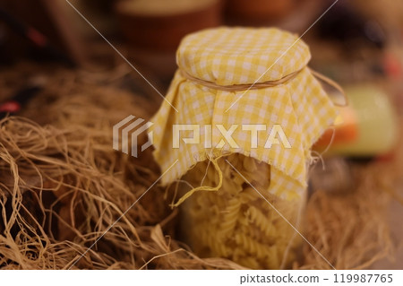 Homemade preserves packed in a charming jar adorned with a delightful yellow checkered cloth 119987765