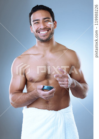 Portrait cream, skincare and man in studio with towel for moisturizer, cosmetic or morning routine on gray background. Luxury, grooming and Asian model with product for lotion, sunscreen or body care 119988226