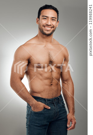 Man, portrait and smiling in studio with abs or muscles, shirtless and grey background with model or bodybuilder. Jeans, strong chest and Asian male person on backdrop, confidence with six pack 119988241