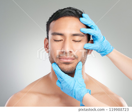 Man, doctor and hands with plastic surgery for medical, skincare or facial treatment on a white studio background. Face of male person with surgeon gloves for reconstruction, cosmetology or beauty 119988723