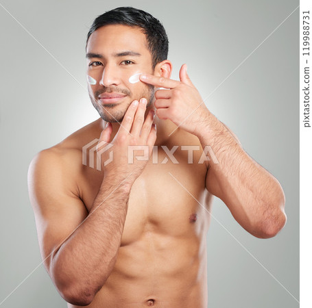 Cosmetics, man and facial cream in studio portrait for wellness, hygiene and grooming or cleaning. Male person, topless and applying product in grey background for health, smooth skin and lotion 119988731