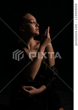 Portrait of Beautiful Woman in Black Silk Dress on Dark Background Portrait of Beautiful Woman in Black Silk Dress on Dark Background 119989009