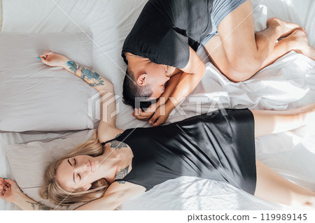 Man and woman sleeping side by side in bedroom on bed 119989145