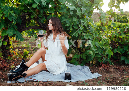 Beautiful woman with a glass of vine in the vineyard before harvesting with a smile 119989228