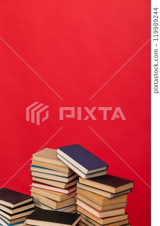 many stacks of educational books to study in the university library on a red background 119989244
