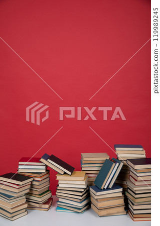 many stacks of educational books to study in the university library on a red background 119989245