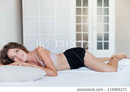 Beautiful woman in lingerie woke up in the morning in the bedroom on the bed Beautiful woman in lingerie woke up in the morning in the bedroom on the bed 119989271
