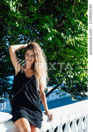 Beautiful fashionable woman in a black summer dress walking around the city Beautiful fashionable woman in a black summer dress walking around the city 119989280