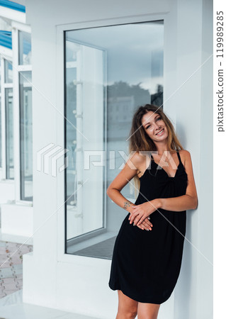 Beautiful slim woman in black summer dress sitting in restaurant 119989285
