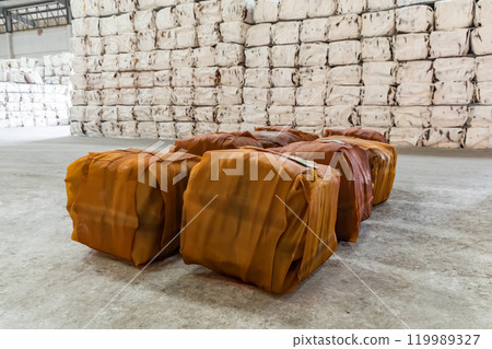 Raw rubber sheet products packed into a cube shape in the warehouse preparing for delivery to customers. Packages were placed on the cement floor. Raw rubber sheet products packed into a cube shape in the warehouse preparing for delivery to customers. Packages were placed on the cement floor. 119989327