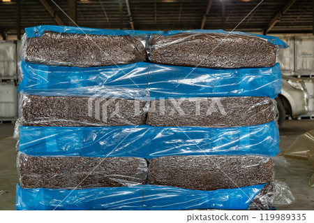 Natural rubber packaged in the plastic sacks, prepared for export delivery, at the distribution center of a rubber company. 119989335