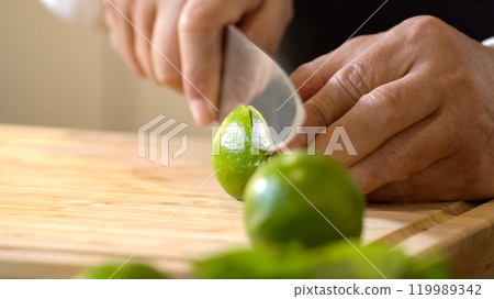 Chef using hands push and roll a lime to juice on a wooden chopping board before cutting and squeezing it. Chef using hands push and roll a lime to juice on a wooden chopping board before cutting and squeezing it. 119989342