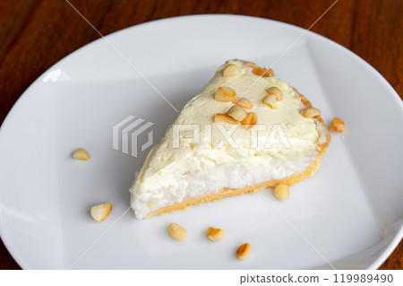 Coconut Cream Pie in the white dish on the wood table that topping with macademia. Shooting in the sunlight. 119989490