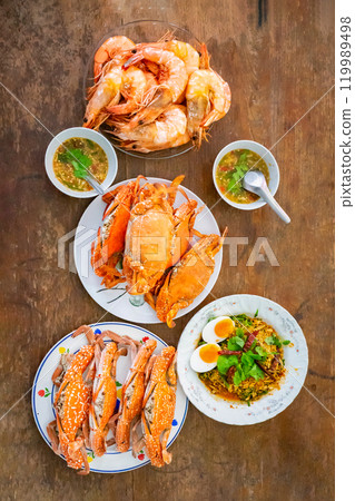 Top view Boiled Crabs and Shrimps in the white ceramic and glass dish on the vintage wooden table. 119989498