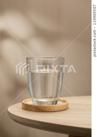A clear glass of drinking water sits on a wooden table. 119989587
