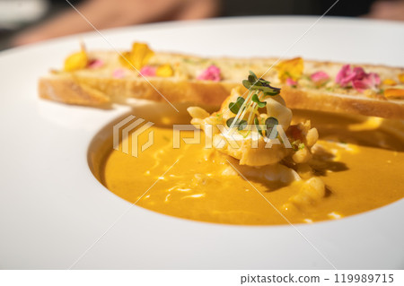Close up to Garlic Bread with Creamy TomYamKung Soup on white dish in studio light, decorated with flower petal on it. Close up to Garlic Bread with Creamy TomYamKung Soup on white dish in studio light, decorated with flower petal on it. 119989715