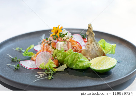 Spicy Raw Salmon Salad Thai food style decorated with Crispy fried fish skin and Yellow Flower on top and micro herb around dish on white background. 119989724