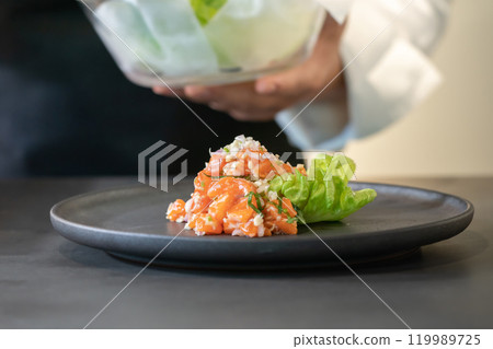 Spicy Raw Salmon Salad Thai food style decorated with Crispy fried fish skin and Yellow Flower on top and micro herb around dish. Ready to serve and eat. 119989725