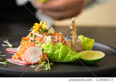 Spicy Raw Salmon Salad Thai food style decorated with Crispy fried fish skin and Yellow Flower on top and micro herb around dish. Ready to serve and eat. 119989727