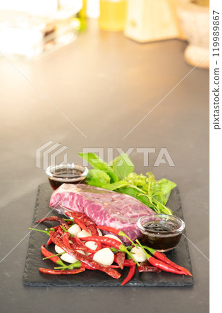 Raw Beef and herb ingredients, basil leaf, garlic, chilli, sauces are prepared on a black stone, slate plate for next cooking process in the Thai food menu, Stir-fried beef basil. Raw Beef and herb ingredients, basil leaf, garlic, chilli, sauces are prepared on a black stone, slate plate for next cooking process in the Thai food menu, Stir-fried beef basil. 119989867